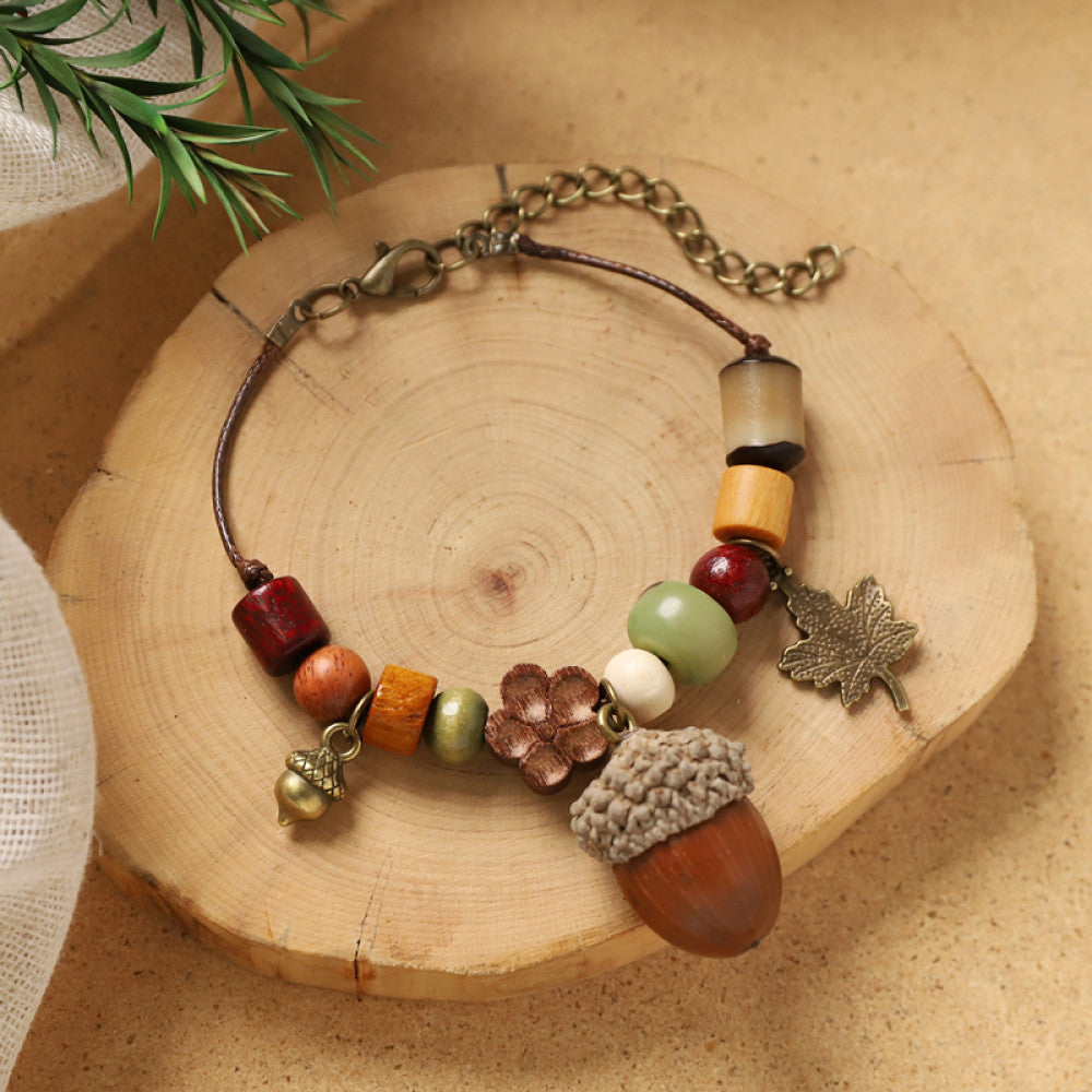 Wooden beads with acorn and leaf charms, forest-inspired rustic charm.