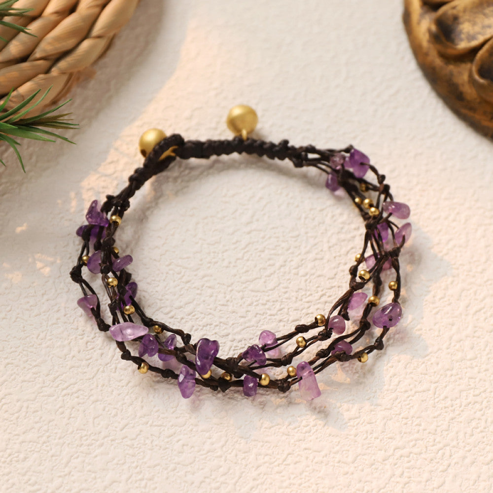 This multi-layered bohemian bracelet features black braided cords adorned with natural amethyst chips and gold beads, finished with golden accent beads. A unique, earthy accessory for everyday style