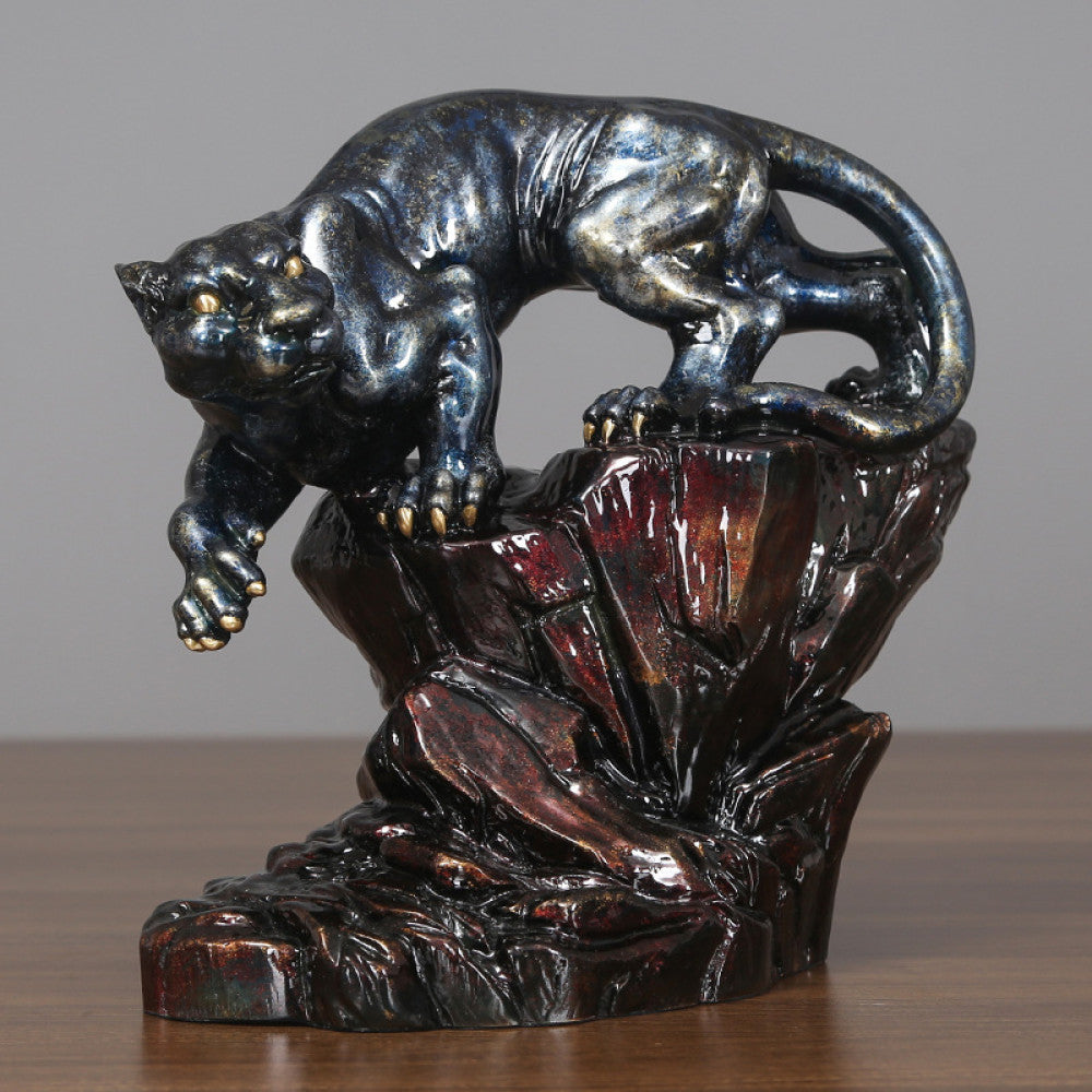 Art Deco style crouching panther statue with blue and metallic finishes, perched on a detailed rocky base (a symbol of strength & courage), displayed on a wooden surface against a gray background