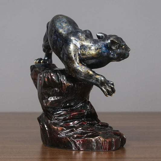 Art Deco style crouching panther statue with blue and metallic finishes, perched on a detailed rocky base (a symbol of strength & courage), displayed on a wooden surface against a gray background 02