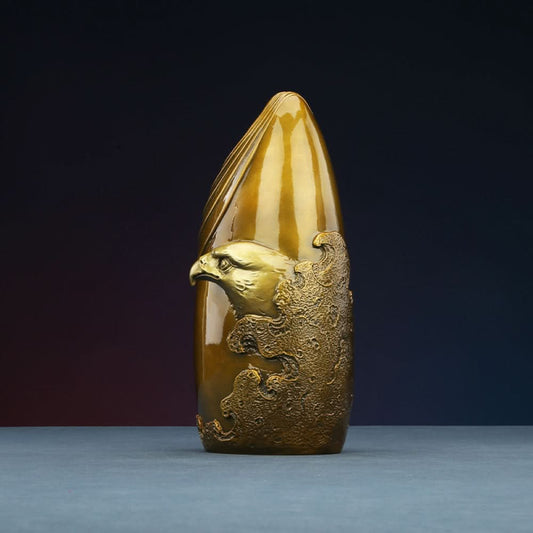 Brass eagle sculpture with textured details, placed on blue surface against dark gradient background