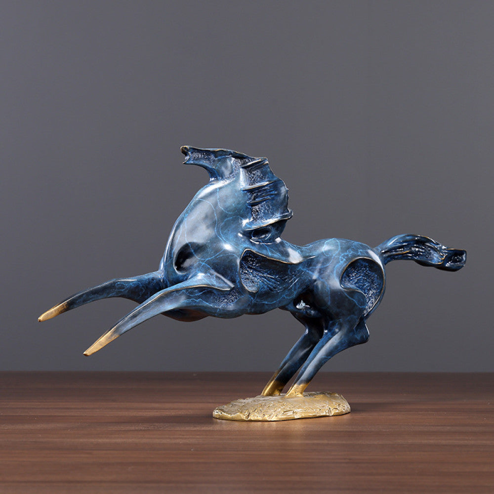 Blue galloping horses statue with golden accents, a symbol of success and strength in Feng Shui, displayed as stylish home decor on a wooden table against a gray background 01