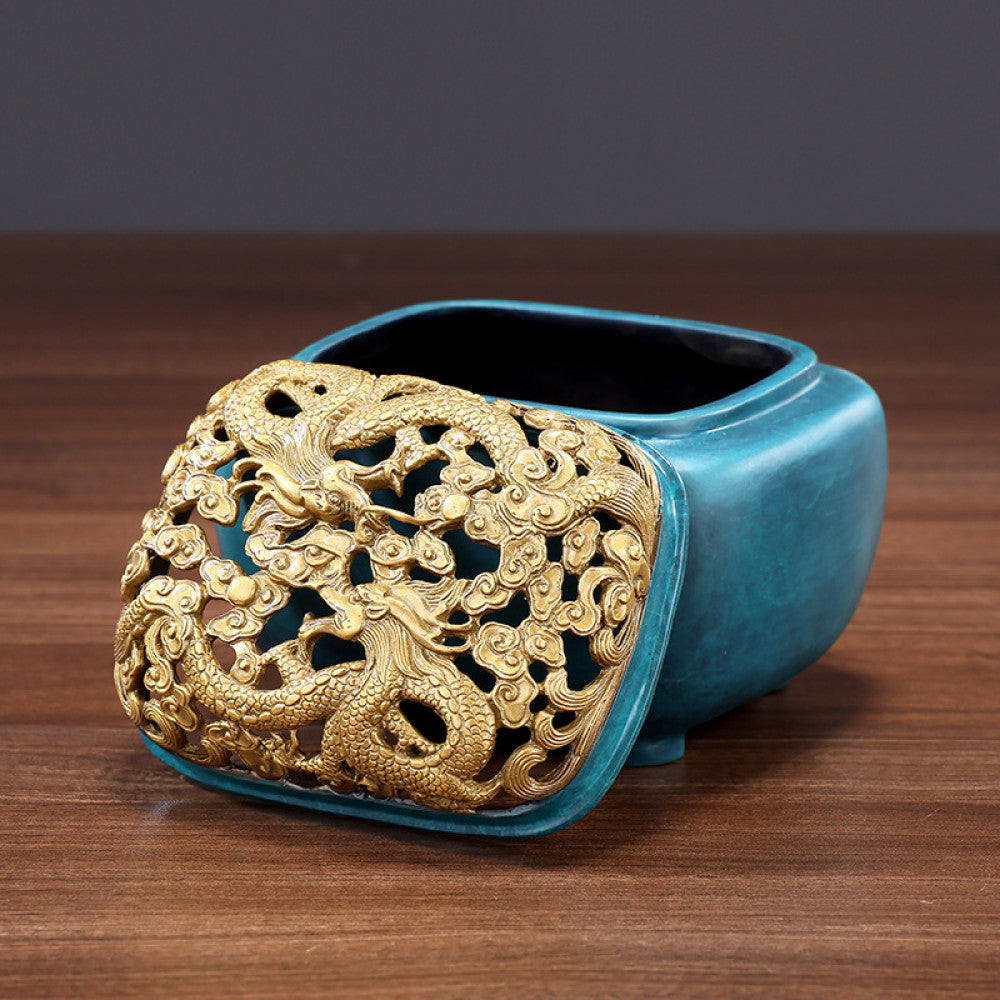 Blue-green bronze Chinese incense burner with intricately carved golden dragon pierced lid, square body, and small feet, a Feng Shui symbol of wealth and protection, displayed as a stylish home decor piece on a wooden surface against a gray background 02