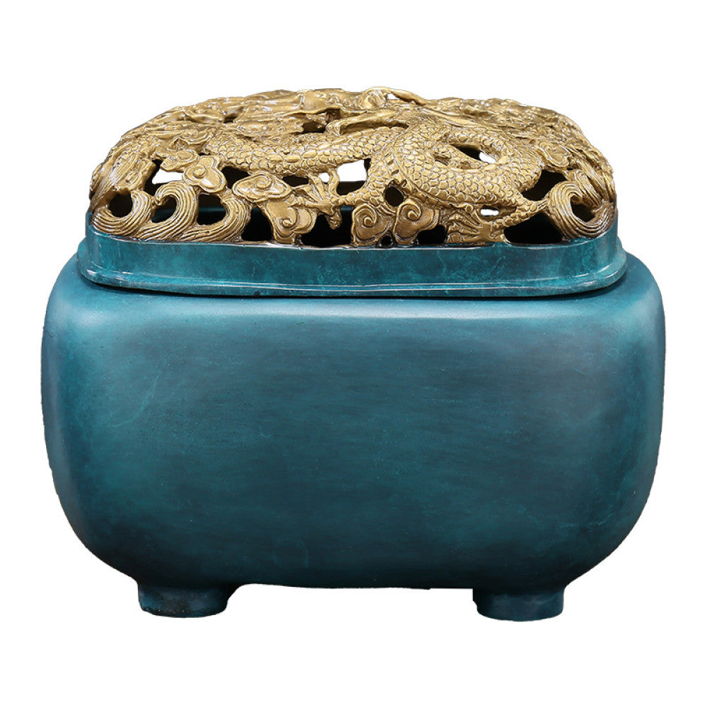 Blue-green bronze Chinese incense burner with intricately carved golden dragon pierced lid, square body, and small feet, a Feng Shui symbol of wealth and protection, displayed as a stylish home decor piece on a wooden surface against a gray background 04