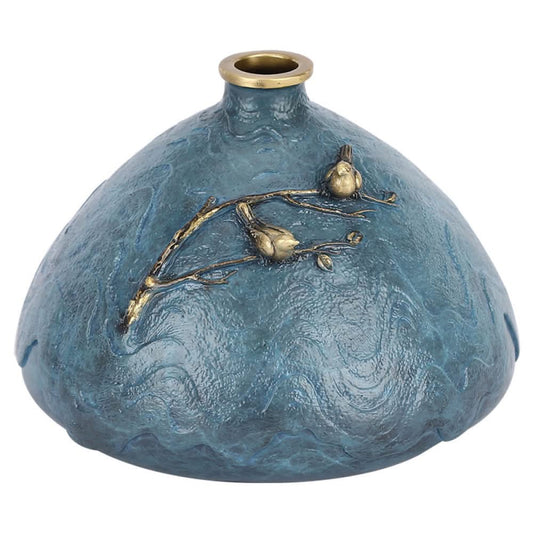 Blue textured art vase with brass branch and bird decoration against white background