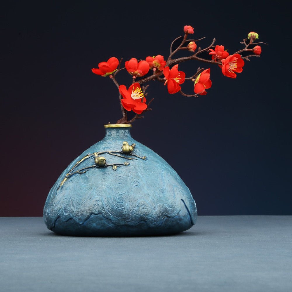 Blue textured art vase with brass branch and bird decoration against white background 01