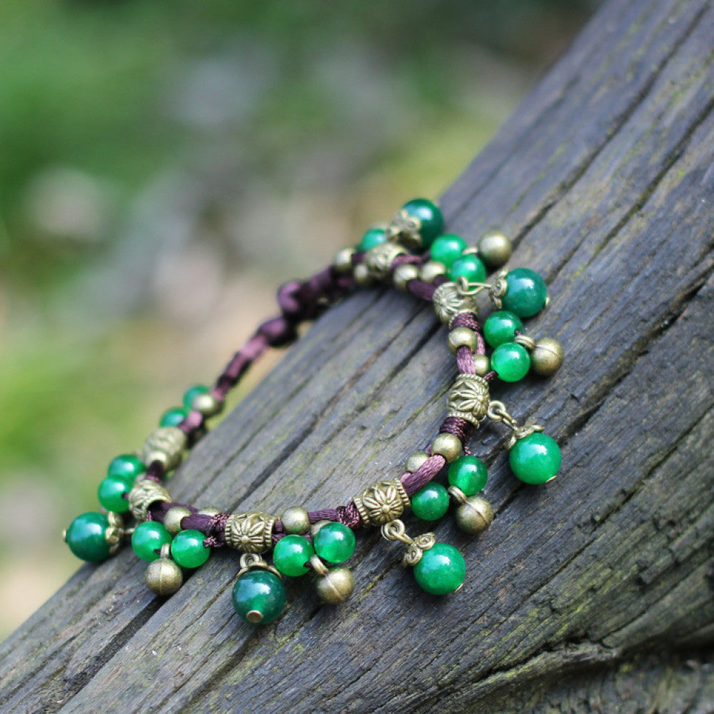 This bohemian anklet features vibrant red beads and delicate green accents on a brown cord, designed for a lightweight, nature-inspired summer look. The adjustable design ensures a comfortable fit for casual, outdoor wear 2