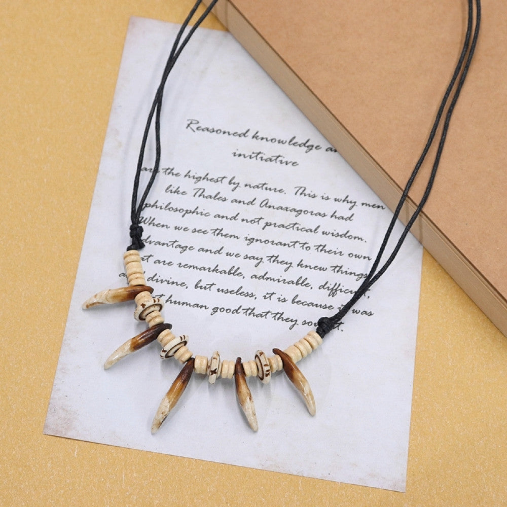 Vintage bohemian tribal necklace with bone accents and black cord, displayed on vintage paper, ideal for ethnic wilderness and boho fashion