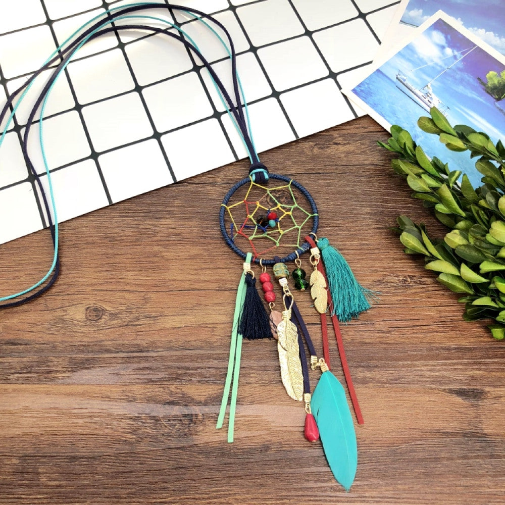 Vintage bohemian dreamcatcher necklace with feather, stone, and tassel accents, displayed on a wooden surface with grid paper and greenery, ideal for spiritual boho fashion enthusiasts 04