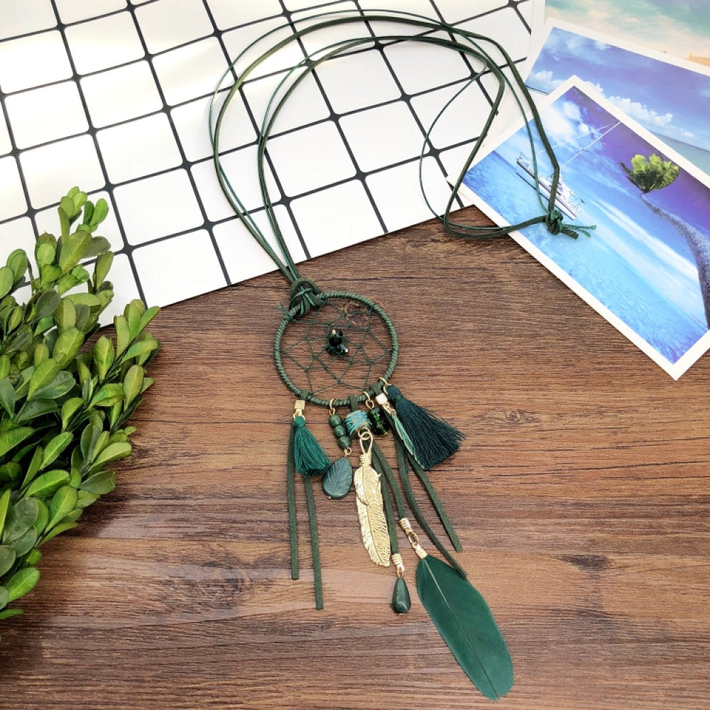 Vintage bohemian dreamcatcher necklace with feather, stone, and tassel accents, displayed on a wooden surface with grid paper and greenery, ideal for spiritual boho fashion enthusiasts 05