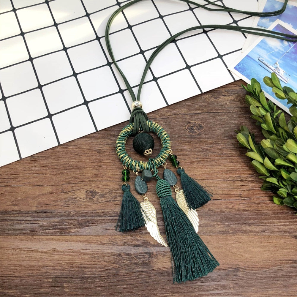 Vintage bohemian dreamcatcher necklace with feather, stone, and tassel accents, displayed on a wooden surface with grid paper and greenery, ideal for spiritual boho fashion enthusiasts 08