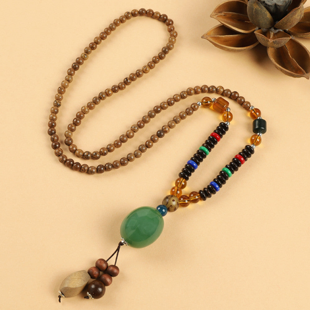 Vintage bohemian ethnic beaded necklace with intricate seed pendant and multi-color beads, ideal for spiritual boho fashion, displayed with a decorative flower against a neutral background 03