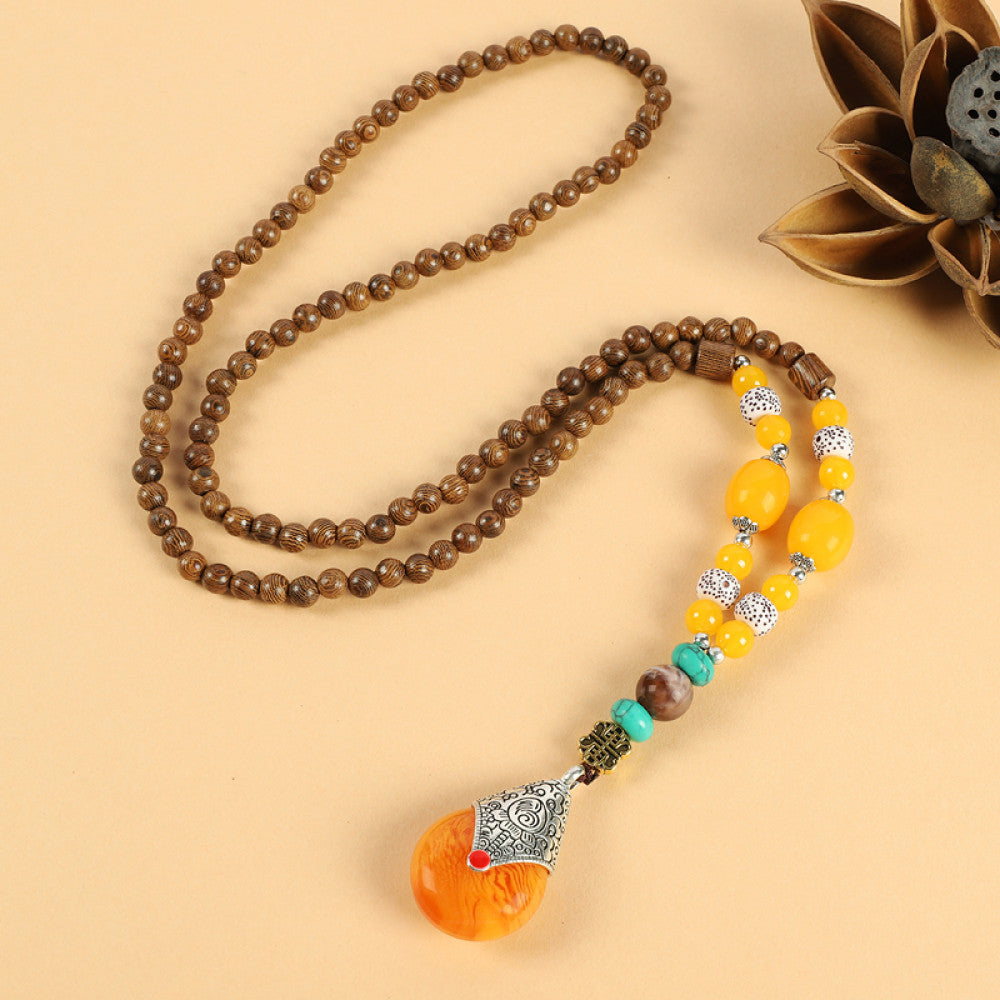Vintage bohemian ethnic beaded necklace with intricate seed pendant and multi-color beads, ideal for spiritual boho fashion, displayed with a decorative flower against a neutral background 08