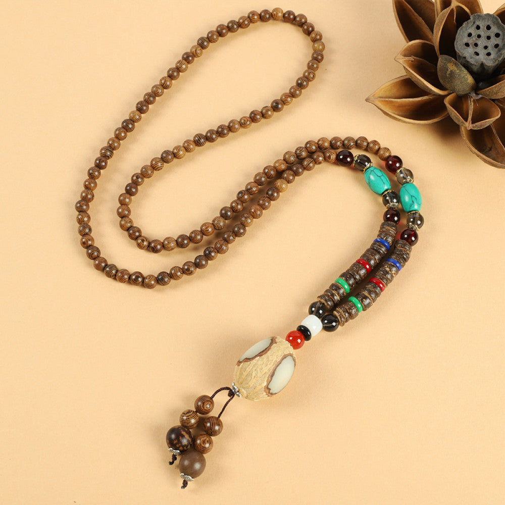 Vintage bohemian ethnic beaded necklace with intricate seed pendant and multi-color beads, ideal for spiritual boho fashion, displayed with a decorative flower against a neutral background 09