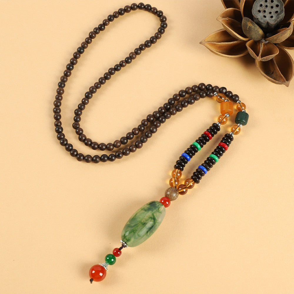 Vintage bohemian ethnic beaded necklace with jade pendant and multi-color beads, ideal for spiritual boho fashion, displayed with a decorative flower against a neutral background