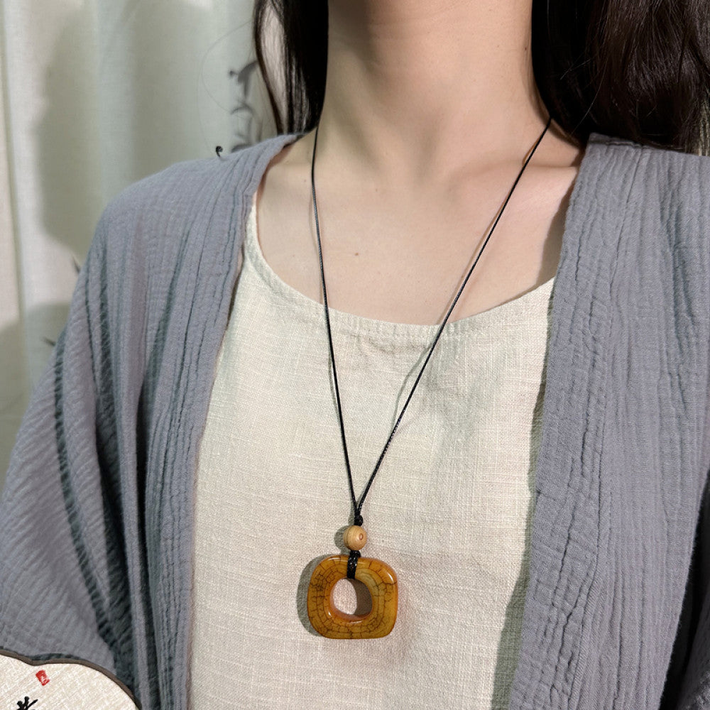 Vintage bohemian ethnic necklace with unique Chinese-style square pendant, featuring earthy tones and black cord, displayed with traditional Chinese calligraphy and decorative flower, ideal for spiritual boho and ethnic fashion enthusiasts 02