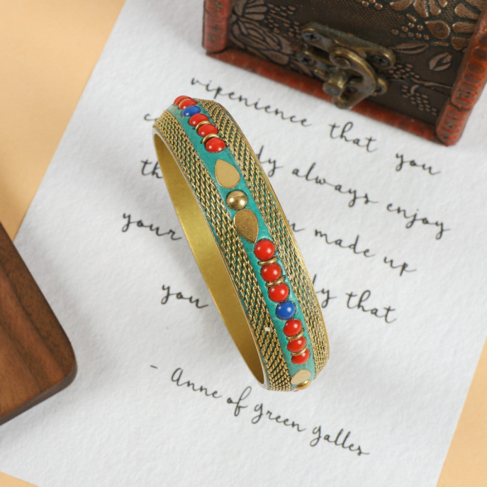 Vintage bohemian ethnic enamel bangle with turquoise and red stone inlays, gold-tone textured design, displayed on paper with decorative text and a vintage box, ideal for boho fashion enthusiasts