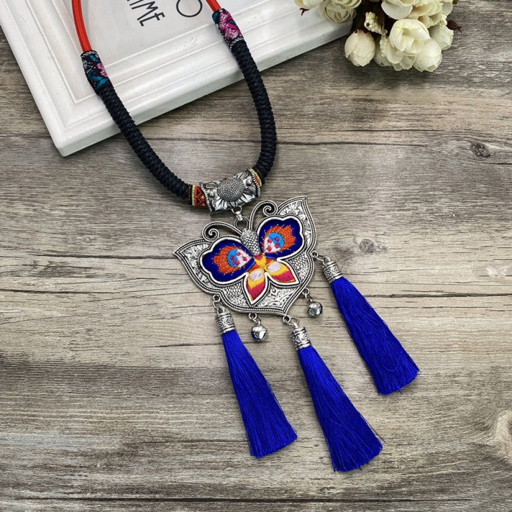 Vintage bohemian ethnic necklace with colorful enamel floral pendant and silver bell tassels, displayed on a wooden surface with decorative accents, ideal for boho fashion enthusiasts 03