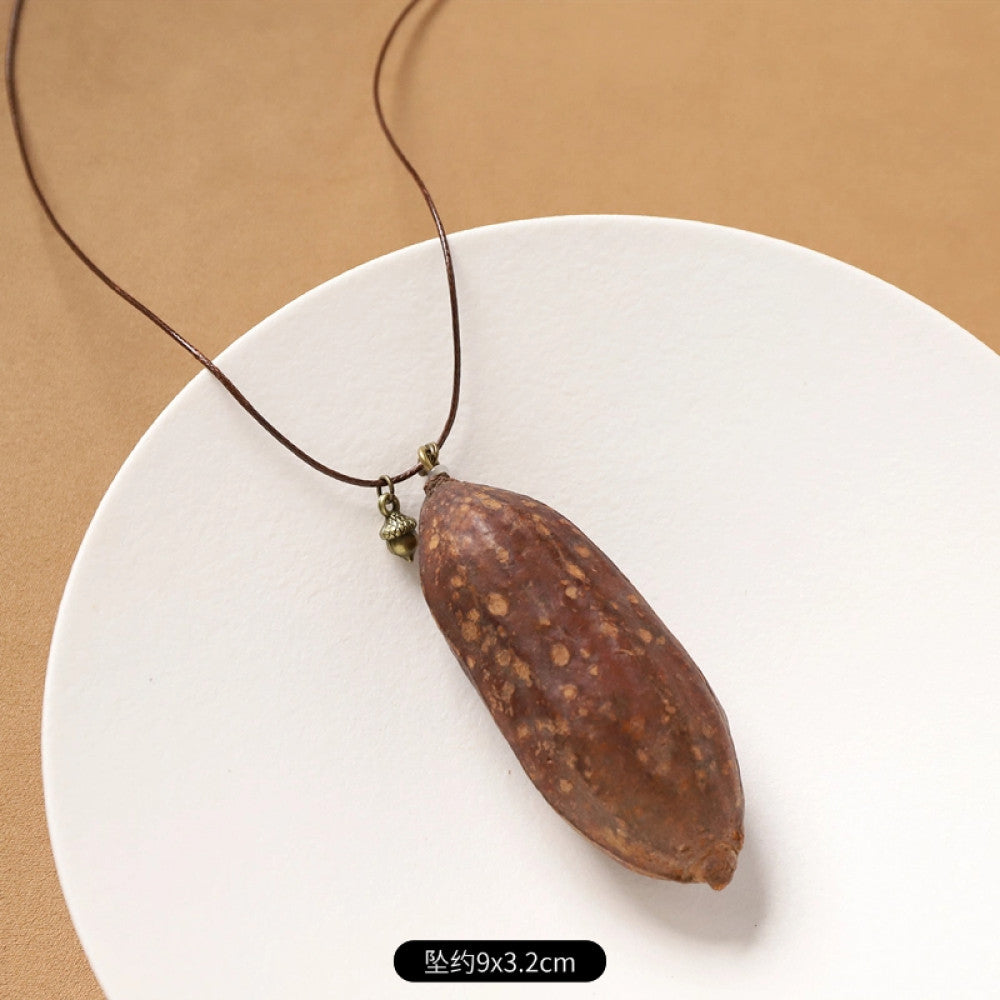 Vintage bohemian ethnic necklace with natural seed pendant, featuring earthy brown tones and cord design, displayed on a white plate against a neutral background, ideal for boho fashion enthusiasts