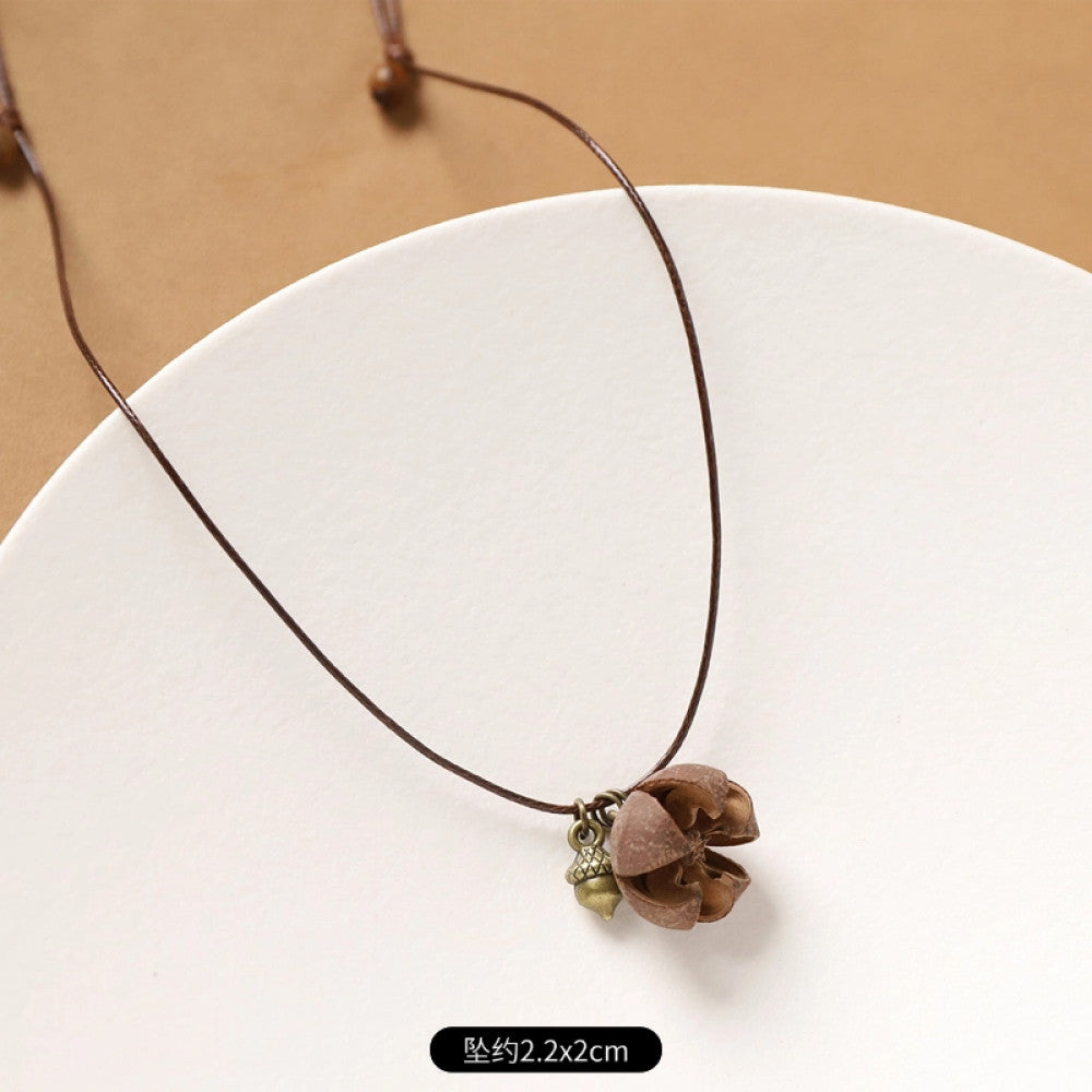 Vintage bohemian ethnic necklace with natural seed pendant, featuring earthy brown tones and cord design, displayed on a white plate against a neutral background, ideal for boho fashion enthusiasts 6