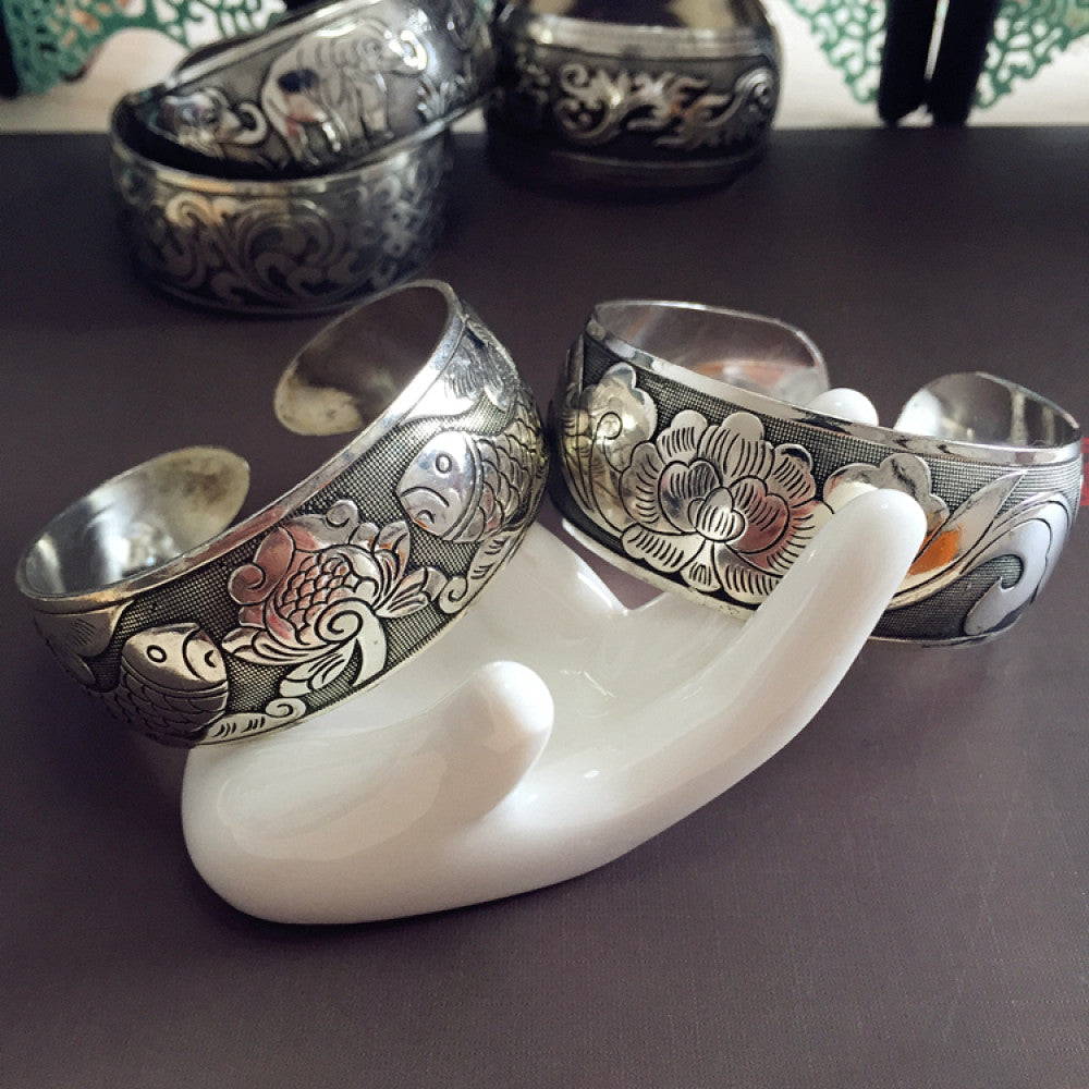 Assorted bohemian vintage ethnic silver-tone engraved cuff bracelet set with fish and floral motifs, displayed on a white hand model, ideal for boho and ethnic fashion enthusiasts