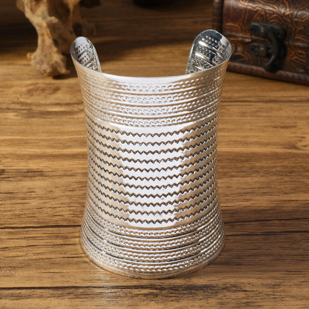 Vintage bohemian ethnic silver-tone cuff bracelet with intricate tribal animal engravings, displayed on a wooden surface with decorative elements, ideal for boho and ethnic fashion enthusiasts 01