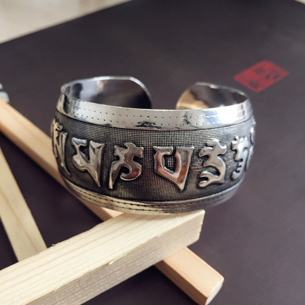 Vintage bohemian ethnic silver-tone cuff bracelet with intricate traditional motif engravings, displayed on wooden accents, ideal for boho and ethnic fashion enthusiasts 07