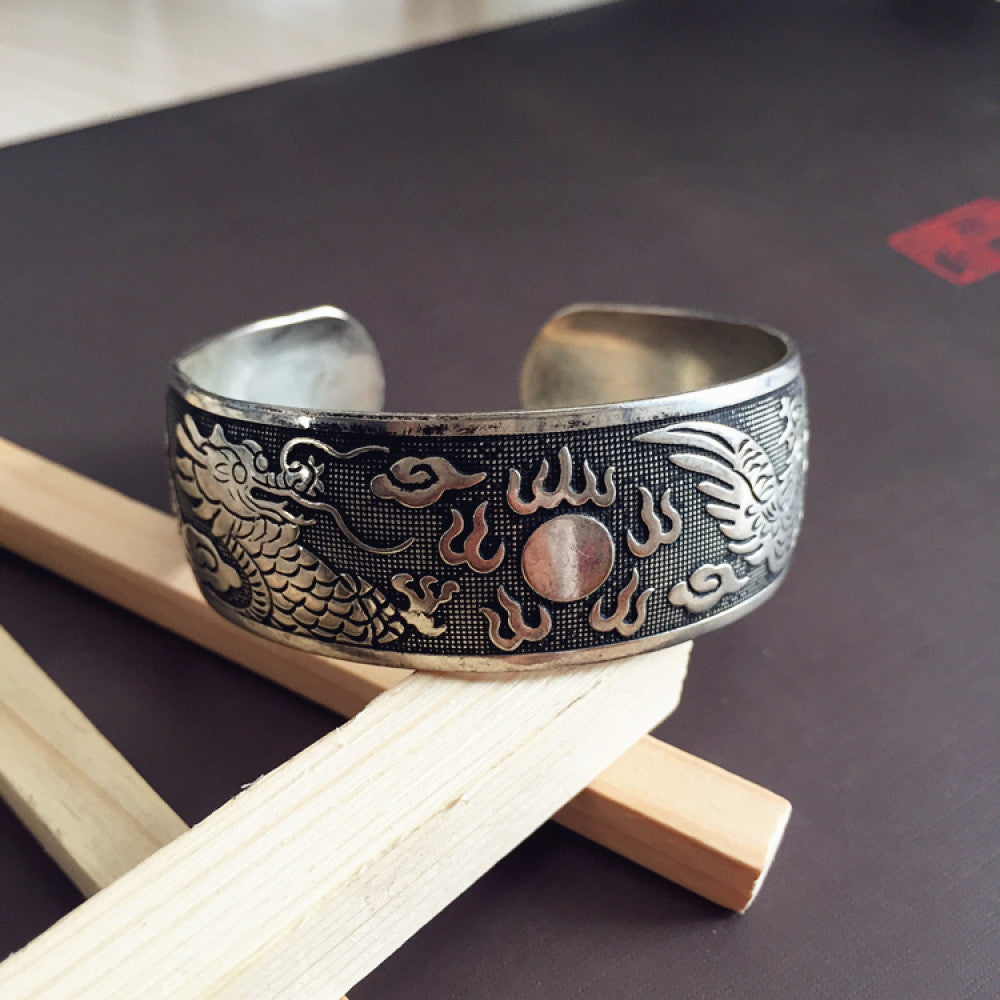 Vintage bohemian ethnic silver-tone cuff bracelet with intricate traditional motif engravings, displayed on wooden accents, ideal for boho and ethnic fashion enthusiasts 08