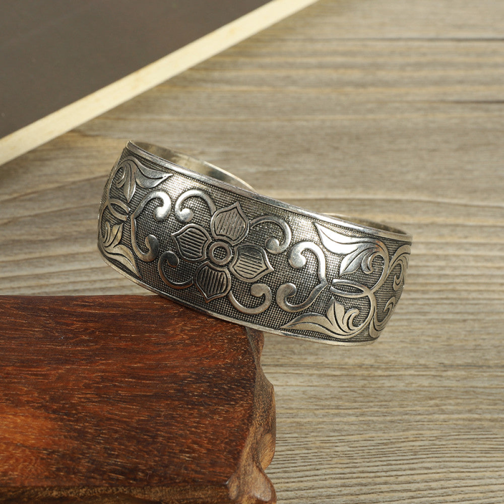 Vintage bohemian ethnic silver-tone cuff bracelet with intricate traditional motif engravings, displayed on wooden accents, ideal for boho and ethnic fashion enthusiasts 11