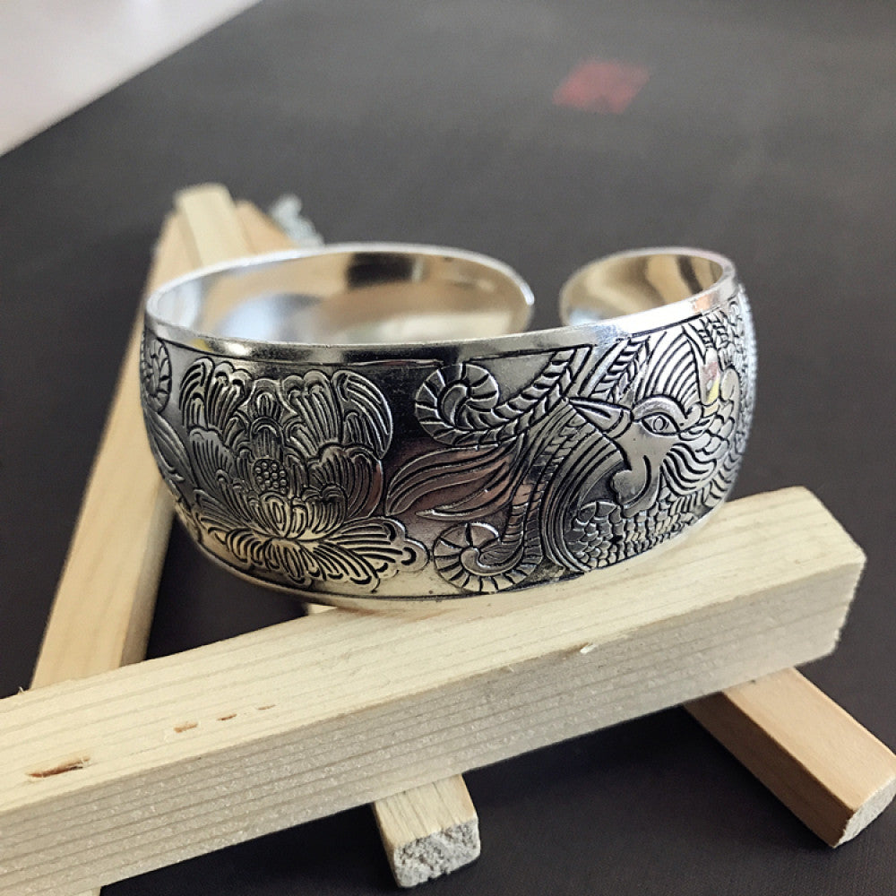 Vintage bohemian ethnic silver-tone cuff bracelet with intricate traditional motif engravings, displayed on wooden accents, ideal for boho and ethnic fashion enthusiasts 12