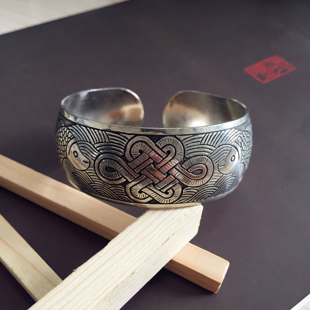 Vintage bohemian ethnic silver-tone cuff bracelet with intricate traditional motif engravings, displayed on wooden accents, ideal for boho and ethnic fashion enthusiasts 14