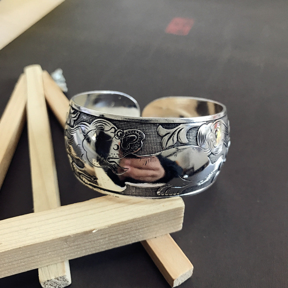 Vintage bohemian ethnic silver-tone engraved filigree cuff bracelet with intricate floral designs, displayed on wooden accents, ideal for boho and ethnic fashion enthusiasts 01