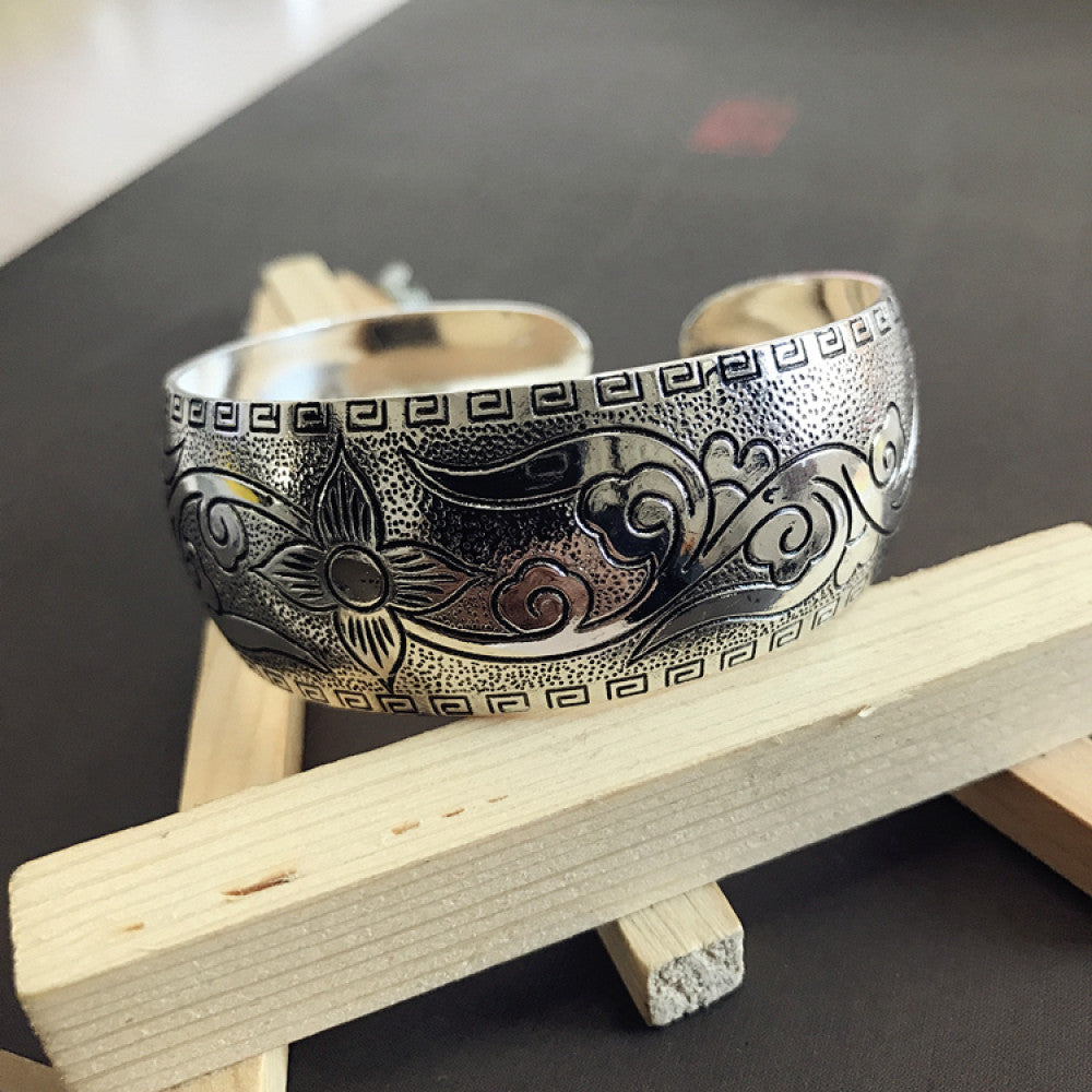 Vintage bohemian ethnic silver-tone engraved filigree cuff bracelet with intricate floral designs, displayed on wooden accents, ideal for boho and ethnic fashion enthusiasts 02