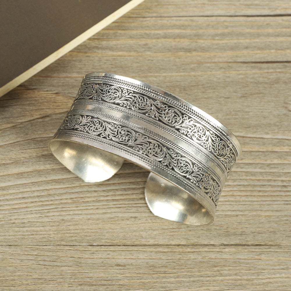 Vintage bohemian ethnic silver-tone engraved filigree cuff bracelet with intricate floral designs, displayed on wooden accents, ideal for boho and ethnic fashion enthusiasts 05