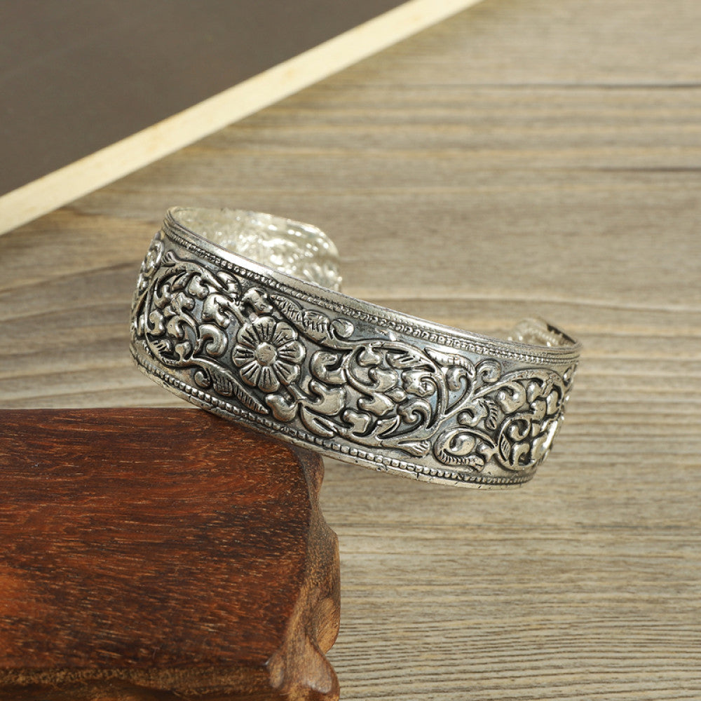 Vintage bohemian ethnic silver-tone engraved filigree cuff bracelet with intricate floral designs, displayed on wooden accents, ideal for boho and ethnic fashion enthusiasts 09