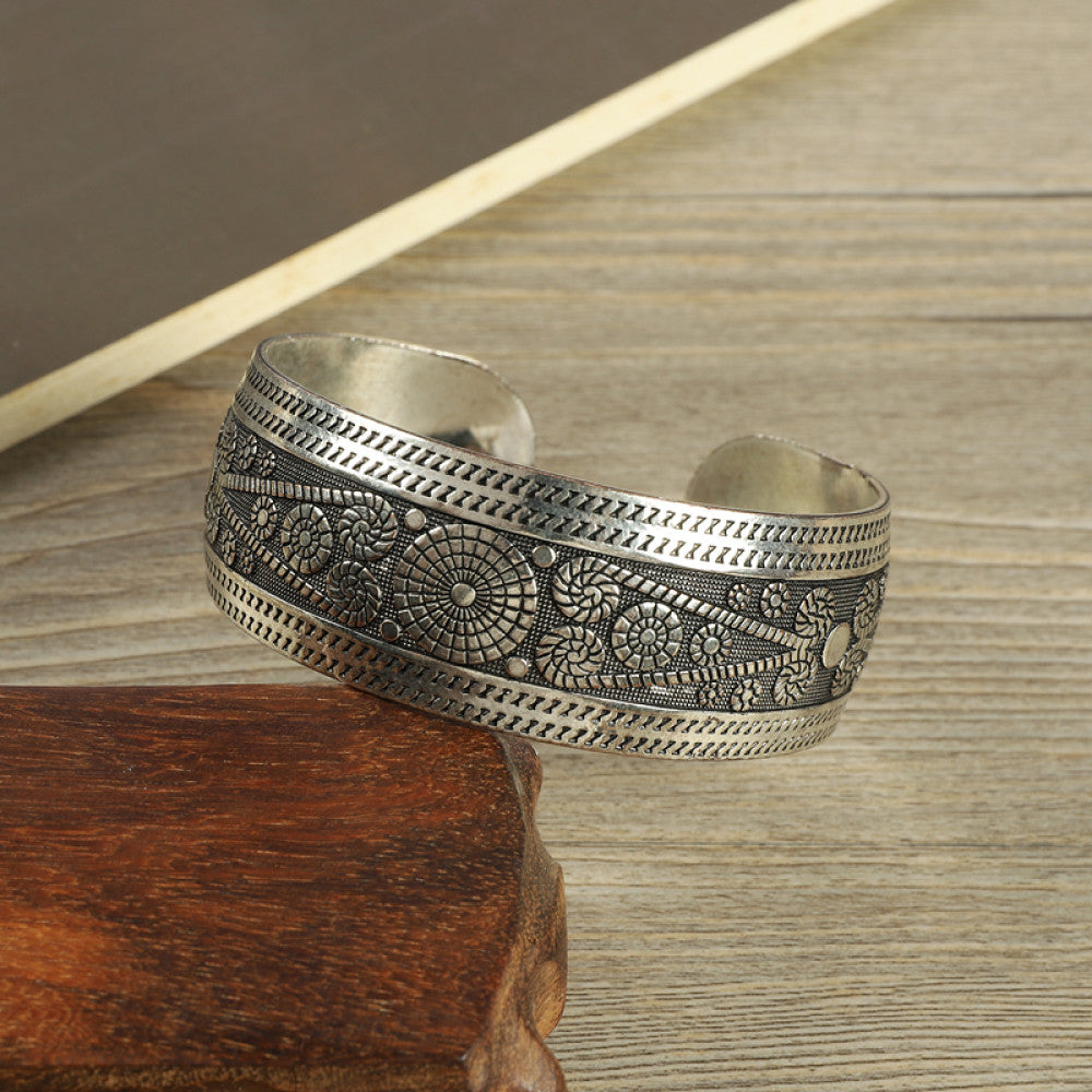 Vintage bohemian ethnic silver-tone engraved filigree cuff bracelet with intricate floral designs, displayed on wooden accents, ideal for boho and ethnic fashion enthusiasts 10