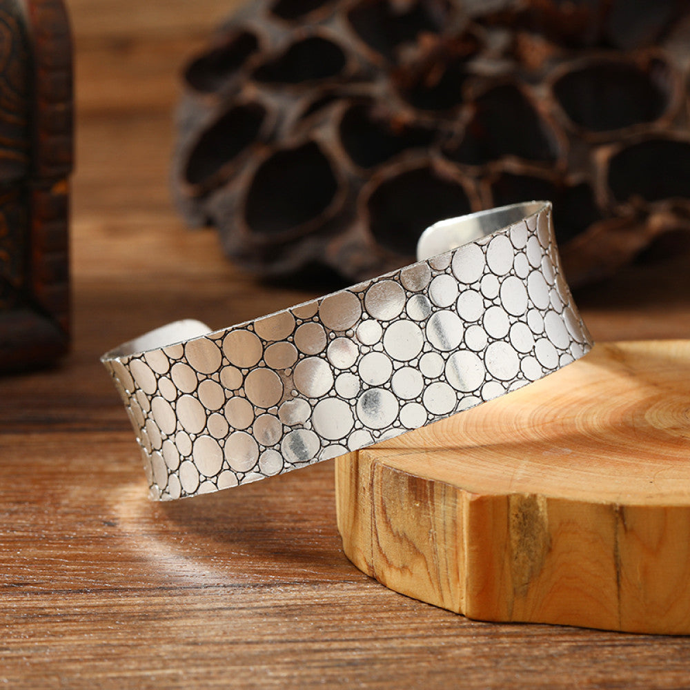 Vintage bohemian ethnic silver-tone cuff bracelet with intricate engraved floral designs, displayed on a wooden surface with rustic decor, ideal for boho and ethnic fashion enthusiasts 05