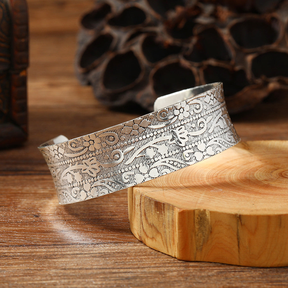Vintage bohemian ethnic silver-tone cuff bracelet with intricate engraved floral designs, displayed on a wooden surface with rustic decor, ideal for boho and ethnic fashion enthusiasts 06