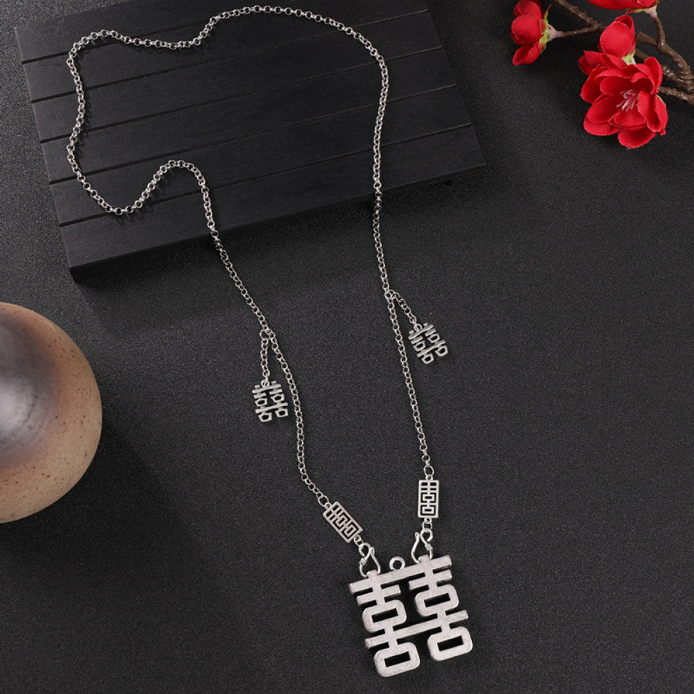 Vintage bohemian ethnic silver-tone necklace with intricate filigree, tassel bells, and ornate pendant, displayed on a dark background with red flowers and decorative accents, ideal for boho and ethnic fashion enthusiasts 02