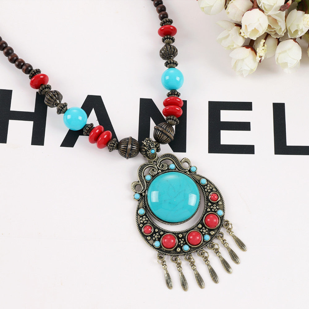Vintage bohemian ethnic necklace with red pendant, turquoise accents, and tassel design, featuring antique bronze details, displayed against a black background with fashion text and Eiffel Tower accent, ideal for boho fashion enthusiasts 04