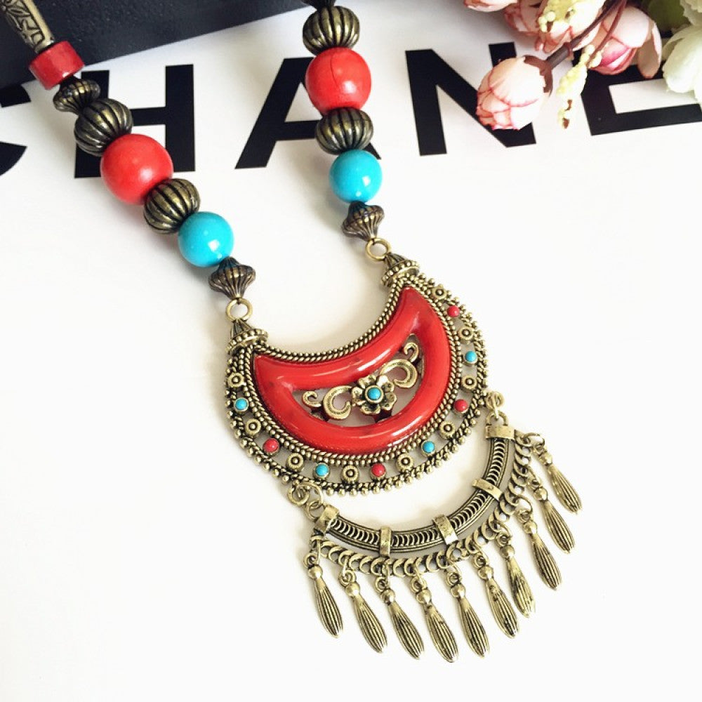 Vintage bohemian ethnic necklace with red pendant, turquoise accents, and tassel design, featuring antique bronze details, displayed against a black background with fashion text and Eiffel Tower accent, ideal for boho fashion enthusiasts 11