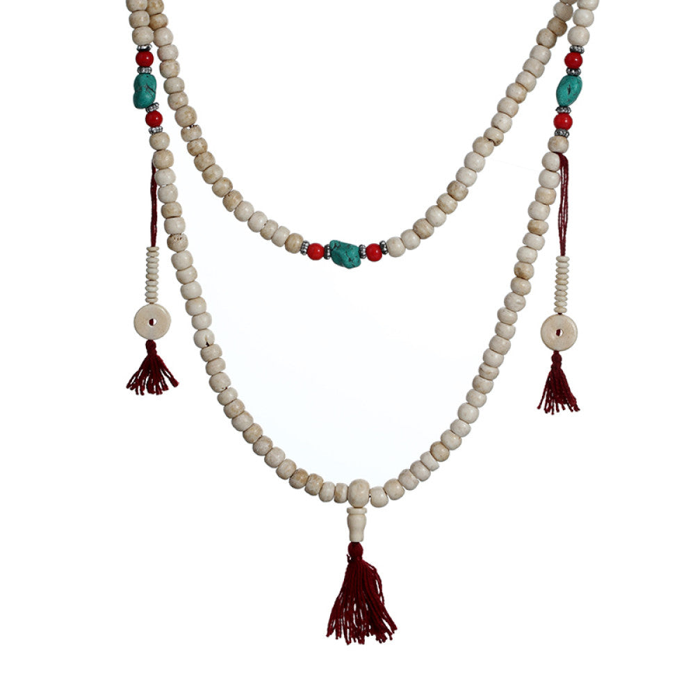 Vintage bohemian ethnic tribal multi-layer beaded necklace with turquoise accents and red tassels, displayed on an old book, ideal for spiritual boho fashion and layering 05
