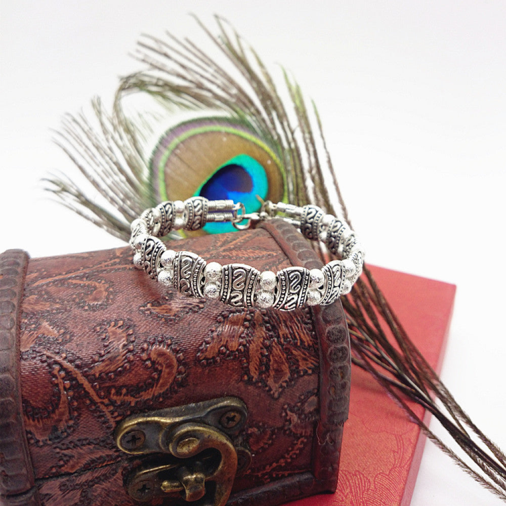 Vintage bohemian ethnic turquoise beaded bracelet with silver engraved accents, displayed on a patterned vintage box with peacock feathers, ideal for boho and ethnic fashion enthusiasts 05