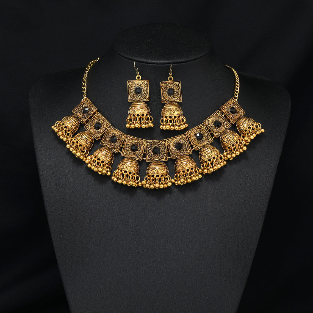 Vintage bohemian ethnic gold-tone necklace and earring set with intricate jhumka design, ideal for traditional or boho-chic occasions, displayed on a black mannequin against a dark background
