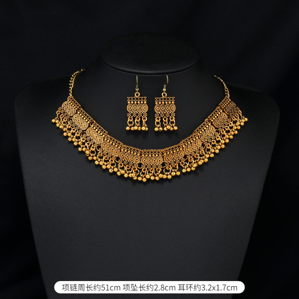 Vintage bohemian ethnic gold-tone necklace and earring set with intricate jhumka design, ideal for traditional or boho-chic occasions, displayed on a black mannequin against a dark background 03