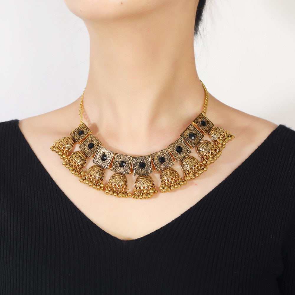 Vintage bohemian ethnic gold-tone necklace and earring set with intricate jhumka design, ideal for traditional or boho-chic occasions, displayed on a black mannequin against a dark background 05