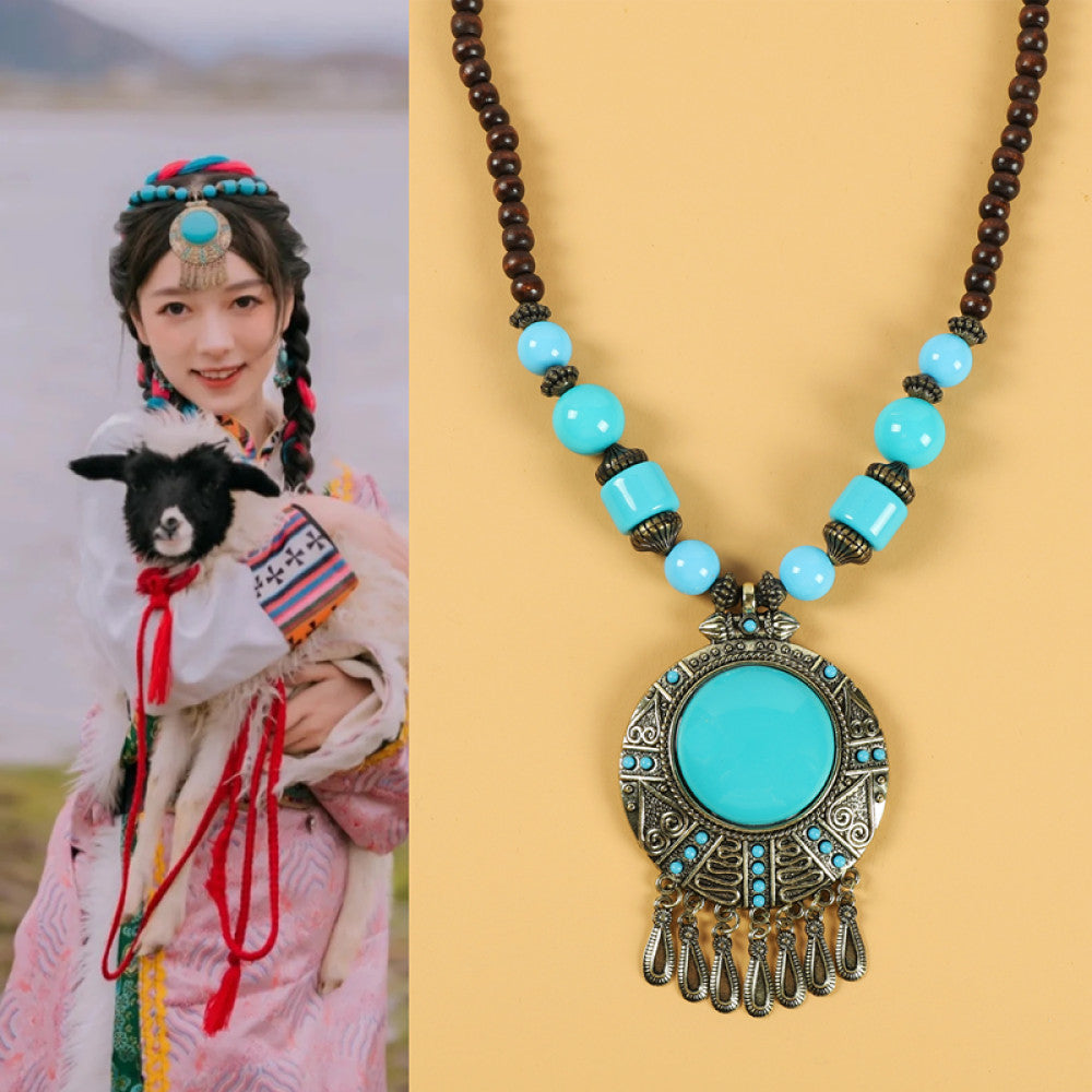 Ethnic tribal style necklace with large circular turquoise pendant, colorful beaded design, and tassel details, ideal for bohemian vintage fashion, displayed alongside a model in traditional ethnic attire 04