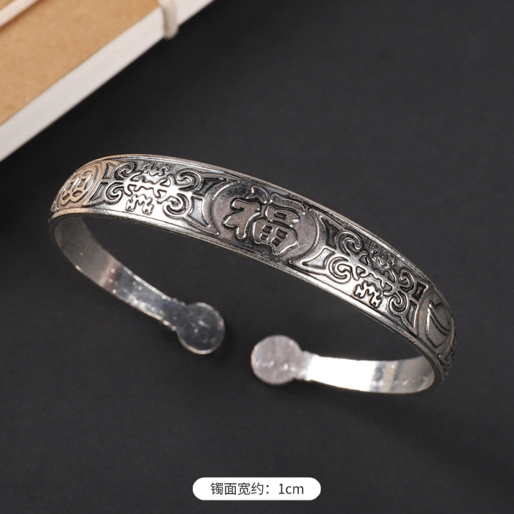 Vintage boho chic silver-tone filigree cuff bracelet with intricate floral designs, styled on a black surface, perfect for bohemian and ethnic fashion lovers in the US 1