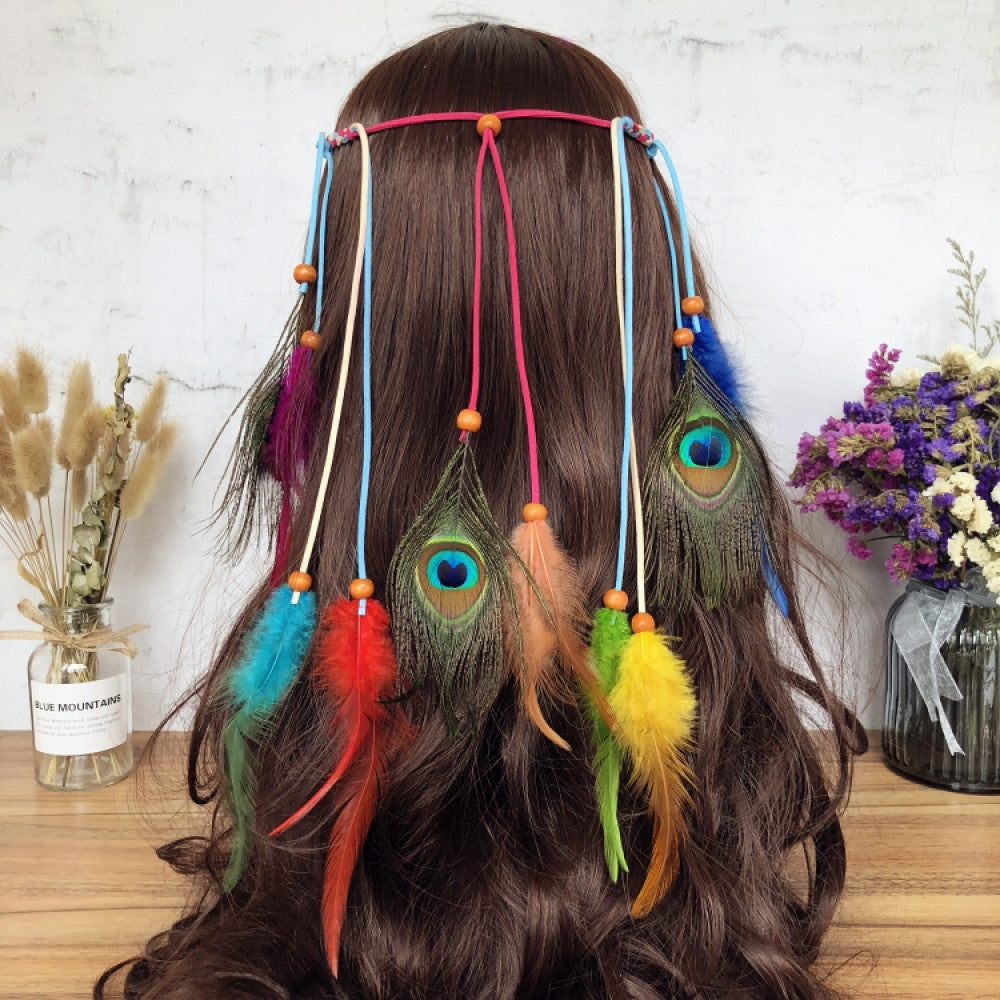 Boho leather cord hair band featuring a vibrant peacock feather, multi color feather tassels, and bead accents displayed on a wooden surface with dried fresh flower arrangements 07