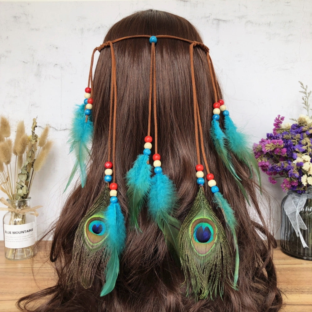 Boho leather cord hair band featuring a vibrant peacock feather, multi color feather tassels, and bead accents displayed on a wooden surface with dried fresh flower arrangements 10